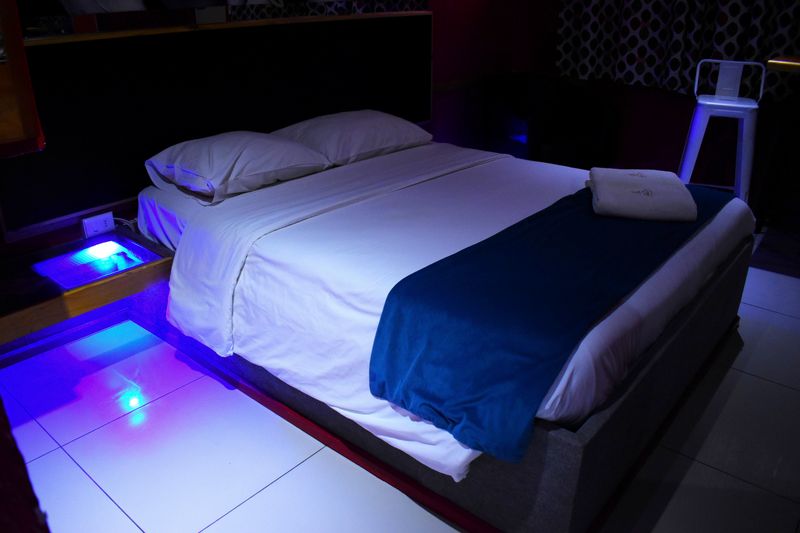 Cama doble con luz azul bajo el velador